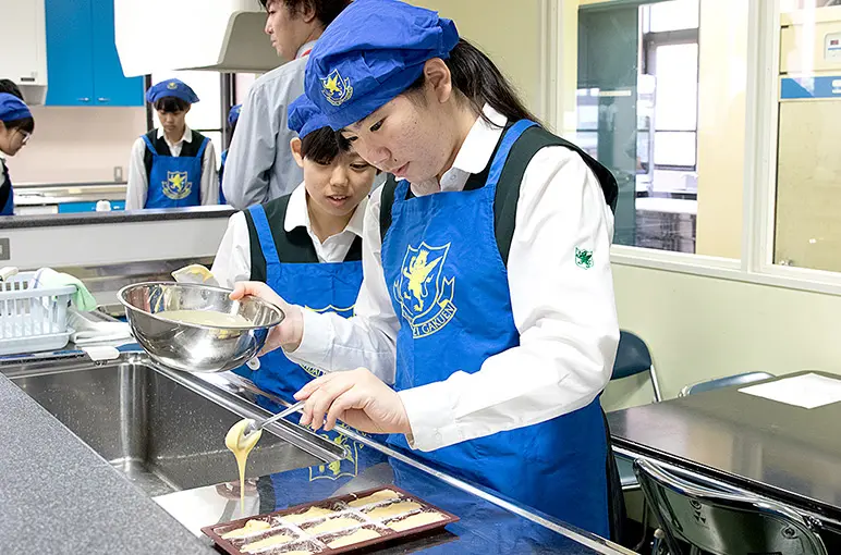조리실에서 앞치마를 두르고 반죽을 틀에 붓는 재학생